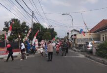 Kawal Ketat Jalur Karnaval HUT RI ke-81, Aiptu Munawan SH Bersama Anggota Polsek Mandirancan Pastikan Lalu Lintas Aman